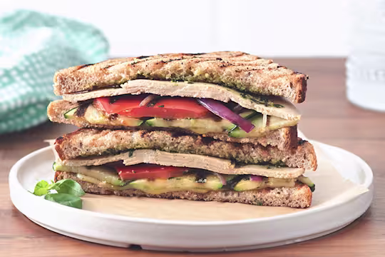 Veggie lunch idea made with Quorn Chicken Free Slices, pesto and grilled vegetables in a sandwich served on a white plate