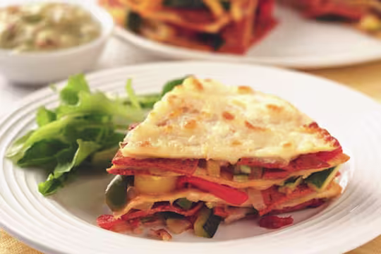 A slice of vegetarian tortilla layered with Quorn Pepperoni Slices, courgettes and peppers served on a plate