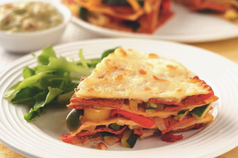 A slice of vegetarian tortilla layered with Quorn Pepperoni Slices, courgettes and peppers served on a plate