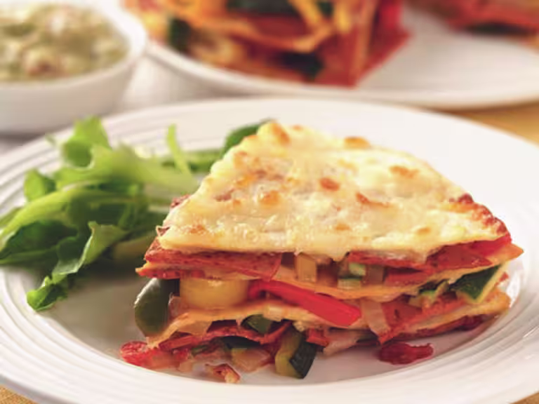 A slice of vegetarian tortilla layered with Quorn Pepperoni Slices, courgettes and peppers served on a plate