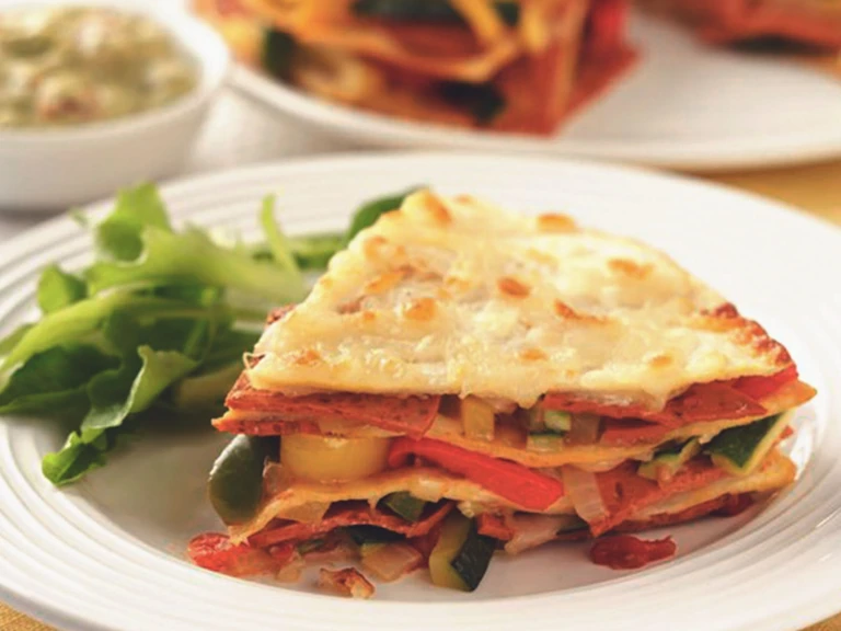 A slice of vegetarian tortilla layered with Quorn Pepperoni Slices, courgettes and peppers served on a plate