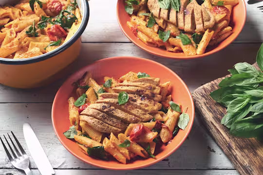 Three bowls of spinach & tomato penne topped with Quorn Vegetarian Fillets served in bowls.