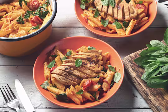 Three bowls of spinach & tomato penne topped with Quorn Vegetarian Fillets served in bowls.