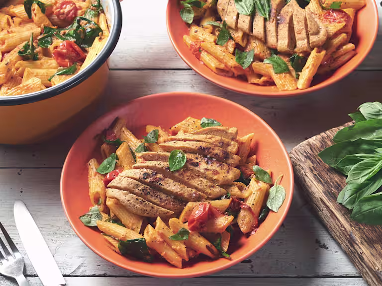 Three bowls of spinach & tomato penne topped with Quorn Vegetarian Fillets served in bowls.