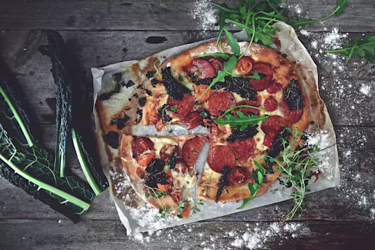 Veggie pizza made with Quorn Vegan Pepperoni Slices, chopped cavolo nero and rocket served on a foil with a slice cut out