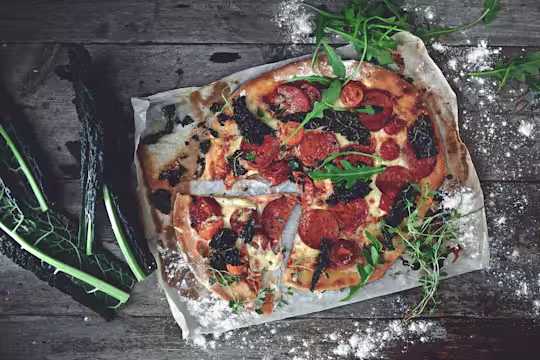 Veggie pizza made with Quorn Vegan Pepperoni Slices, chopped cavolo nero and rocket served on a foil with a slice cut out