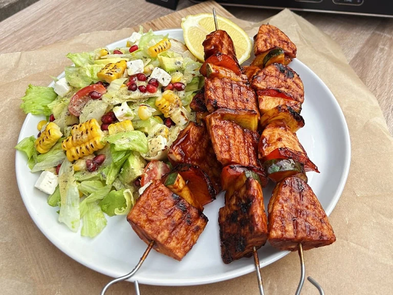 Three Quorn Vegetarian BBQ Skewers and a side of citrus corn salad served on a white dish.