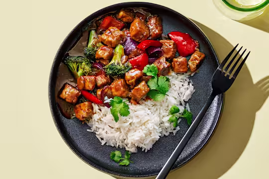 Quorn Vegetarisk Teriyaki gjord med Quorn-bitar, serverad tillsammans med vit ris på en mörk tallrik.