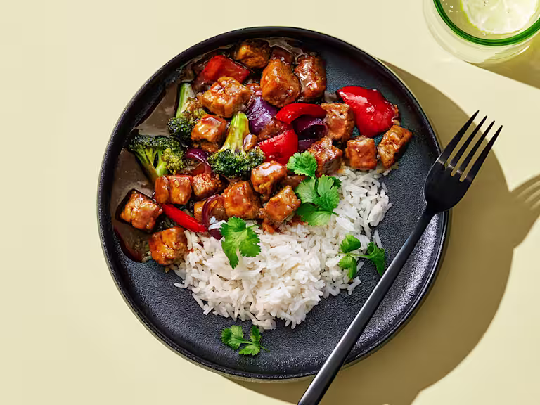 Quorn Vegetarisk Teriyaki gjord med Quorn-bitar, serverad tillsammans med vit ris på en mörk tallrik.