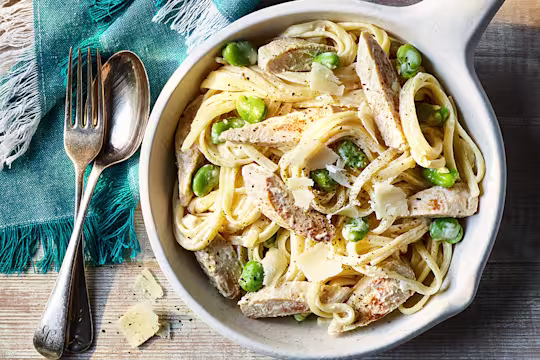 Creamy Crème Fraiche Pasta with Quorn Fillets served in a white dish with a fork and spoon on the side.