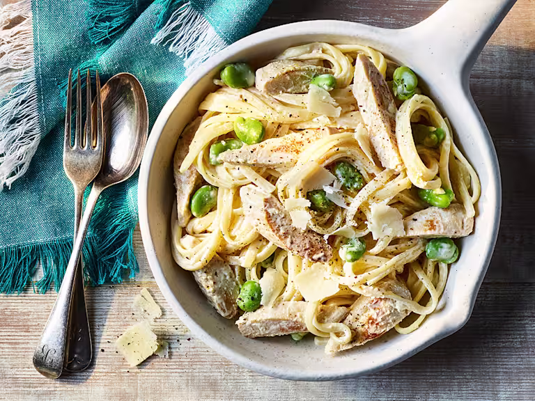 Creamy Crème Fraiche Pasta with Quorn Fillets served in a white dish with a fork and spoon on the side.