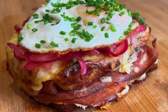 Quorn Finely Sliced Ham and Cheese vegetarian Toastie topped with pink pickled onions, a fried egg and fresh chives.