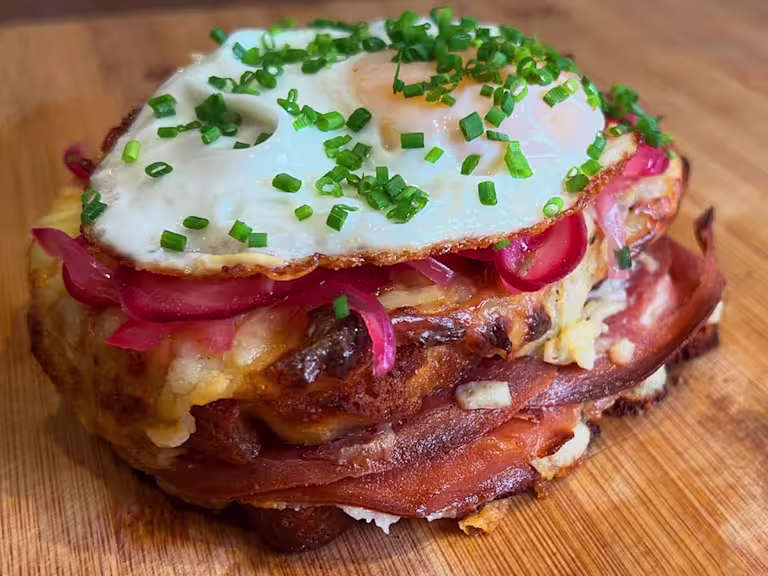 Quorn Finely Sliced Ham and Cheese vegetarian Toastie topped with pink pickled onions, a fried egg and fresh chives.