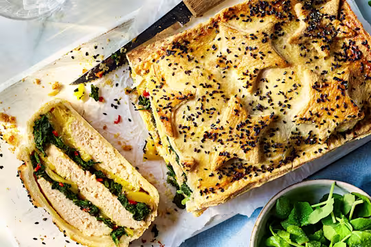 Vegetarian Coronation Chicken Pie on a wooden board with a side salad.