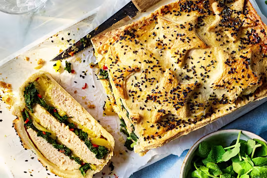 Vegetarian Coronation Chicken Pie on a wooden board with a side salad.