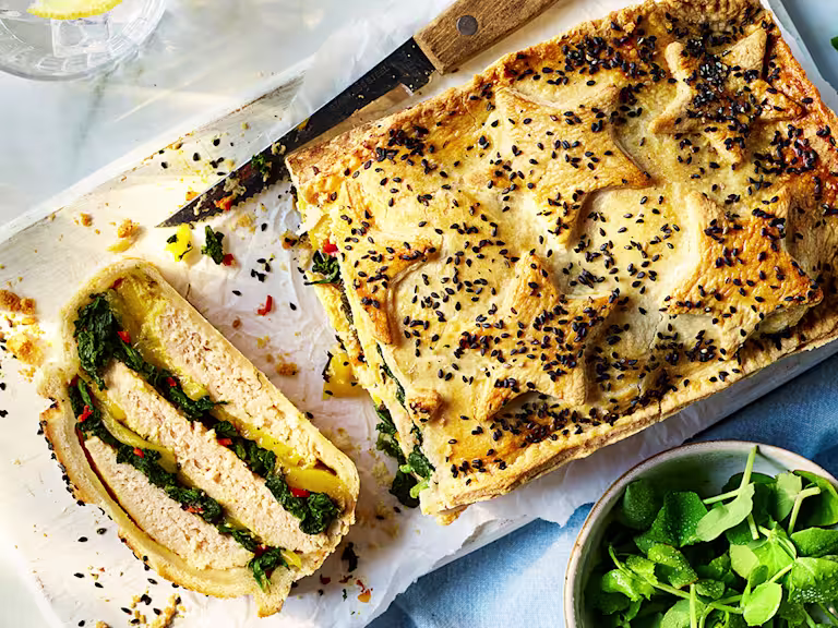 Vegetarian Coronation Chicken Pie on a wooden board with a side salad.