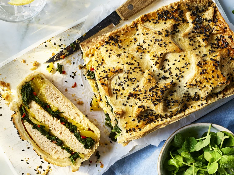Vegetarian Coronation Chicken Pie on a wooden board with a side salad. 