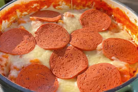 Cheese and Quorn Pepperoni topped pizza orzo in a casserole dish on a table.