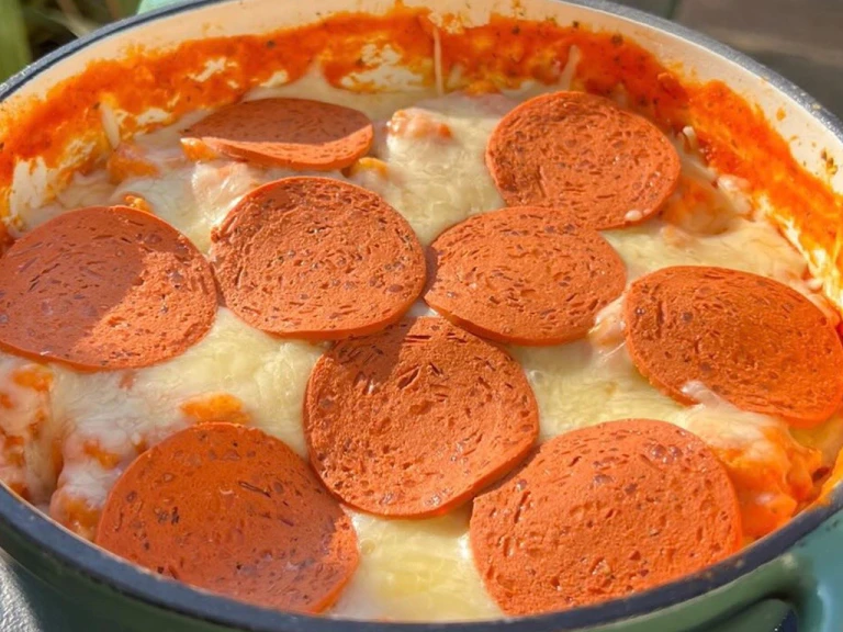 Cheese and Quorn Pepperoni topped pizza orzo in a casserole dish on a table.