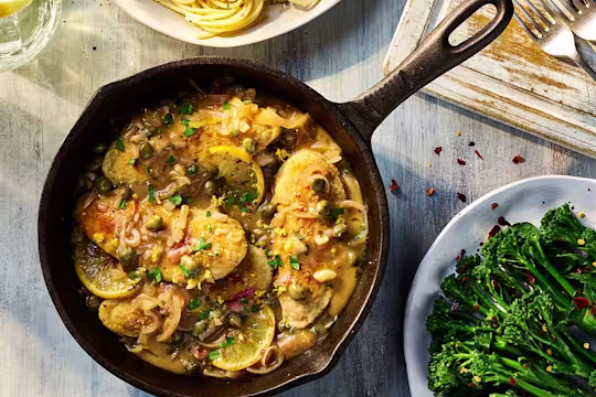 Vegetarian Chicken Piccata with Quorn Fillets served in a dark dish with a side of broccoli.