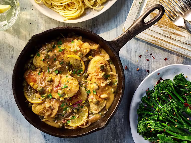 Vegetarian Chicken Piccata with Quorn Fillets served in a dark dish with a side of broccoli.