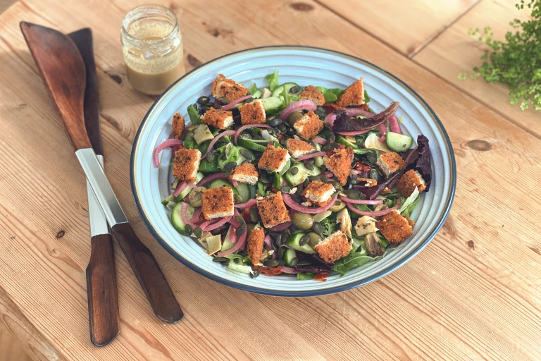 A garden salad topped with pumpkin seeds and diced Quorn Vegan Hot & Spicy burger patties.