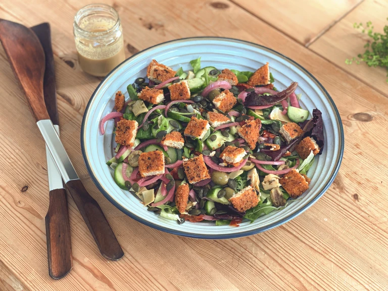 A garden salad topped with pumpkin seeds and diced Quorn Vegan Hot & Spicy burger patties.