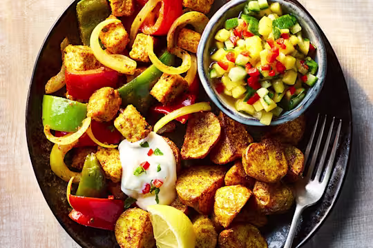 Quorn Pieces Tikka with Bombay potatoes and mango and cucumber chutney on a plate