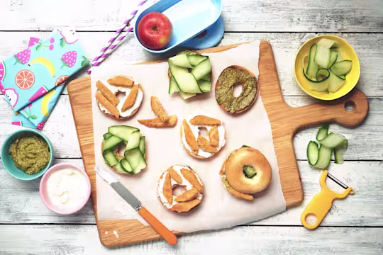 Easy lunch recipe of bagels on a wooden board topped with cucumber, pesto and Quorn Roast Mini Fillets