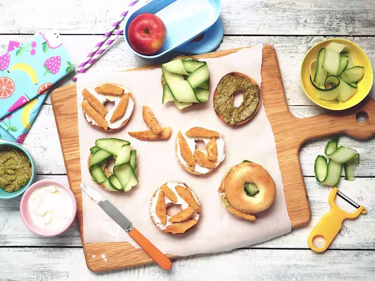 Easy lunch recipe of bagels on a wooden board topped with cucumber, pesto and Quorn Roast Mini Fillets