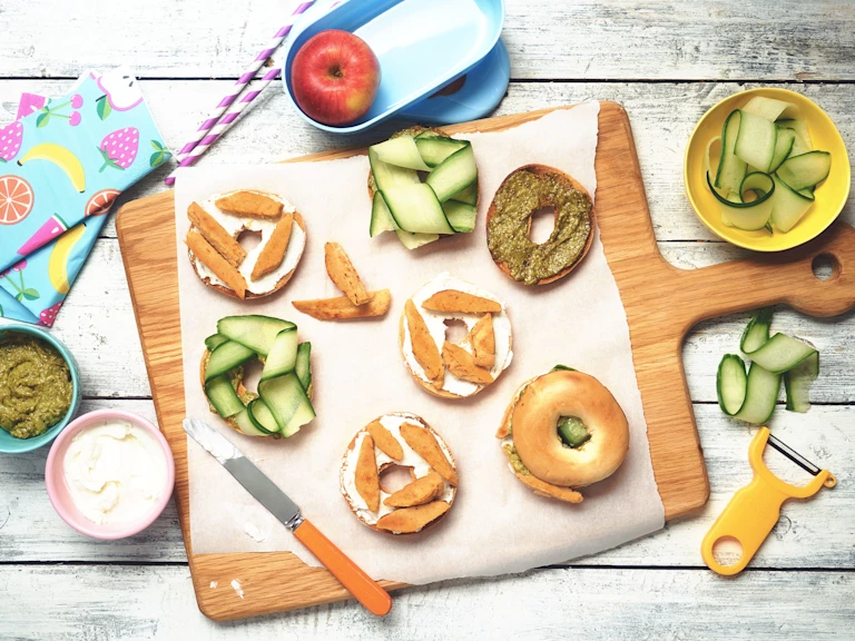 Easy lunch recipe of bagels on a wooden board topped with cucumber, pesto and Quorn Roast Mini Fillets