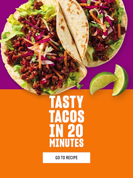 Two soft shell tacos filled with Quorn Mince shredded lettuce and colourful slaw on a vibrant purple background with lime wedges. Bold white text on an orange background reads Tasty Tacos in 20 Minutes with a Go to Recipe button