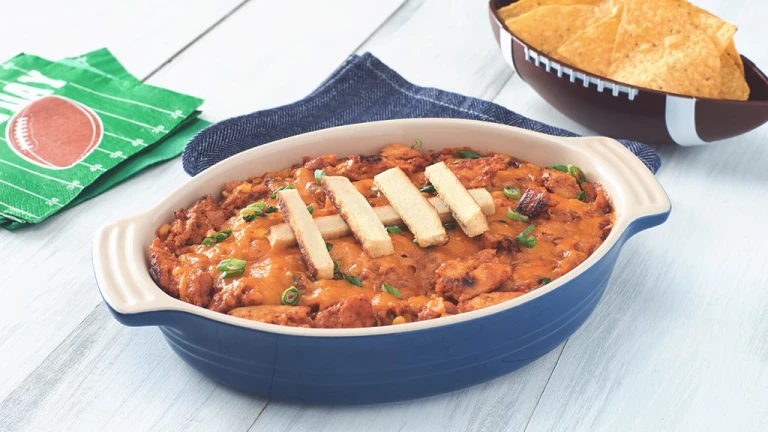 A blue oblong-shaped dish filled with bbq chickenless dip with Quorn Fillet slices arranged on top to make the dish resemble a football.