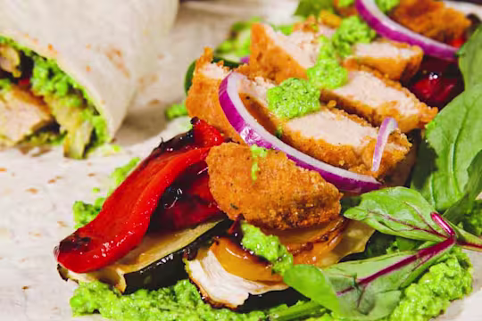 Quorn Crunchy Fillet Burger Vegan Wrap sliced in half to show the filling with an open wrap in the shot.
