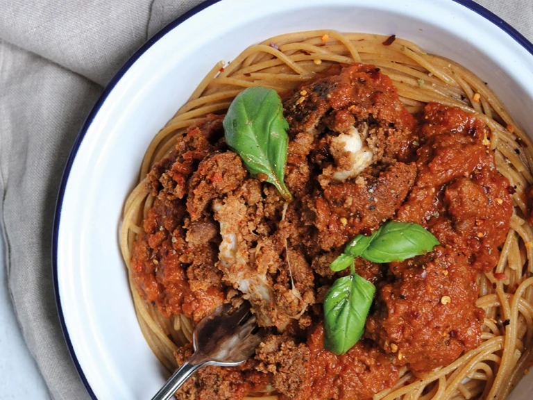 Meat-free meatballs made with Quorn Mince and stuffed with mozzarella cheese sit atop vegetarian arrabiata sauce and whole-wheat spaghetti in an enamel dish garnished with basil.