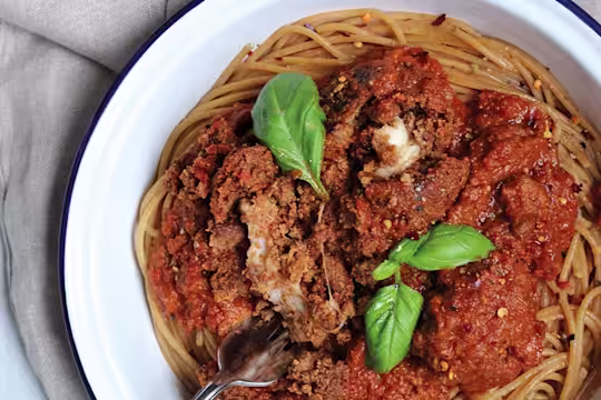 Meat-free meatballs made with Quorn Mince and stuffed with mozzarella cheese sit atop vegetarian arrabiata sauce and whole-wheat spaghetti in an enamel dish garnished with basil.
