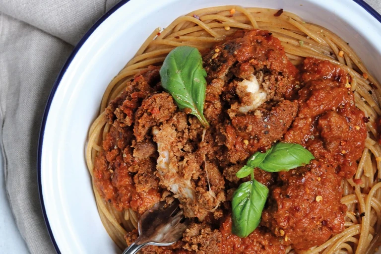 Meat-free meatballs made with Quorn Mince and stuffed with mozzarella cheese sit atop vegetarian arrabiata sauce and whole-wheat spaghetti in an enamel dish garnished with basil.