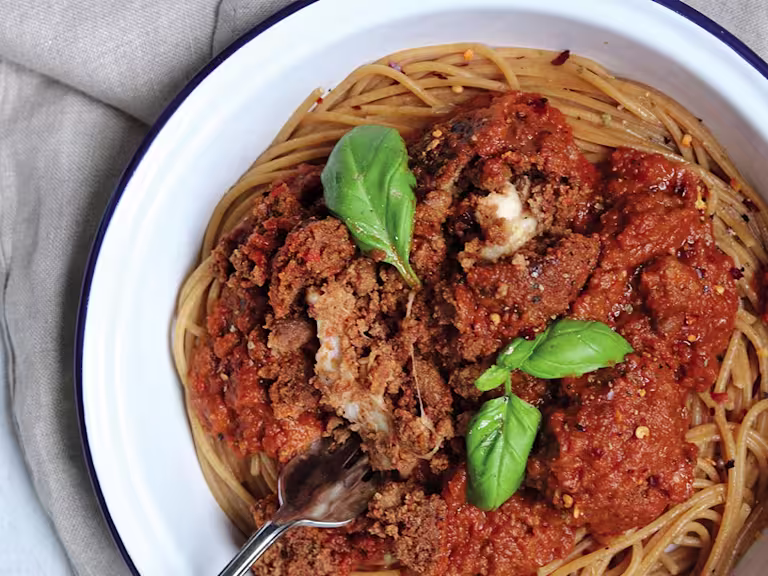 Meat-free meatballs made with Quorn Mince and stuffed with mozzarella cheese sit atop vegetarian arrabiata sauce and whole-wheat spaghetti in an enamel dish garnished with basil.