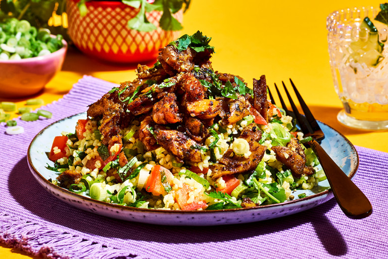A bulgur wheat tabbouleh salad made with Quorn Makes Amazing Turkish Style Kebab on a lilac placemat on a marigold backdrop.