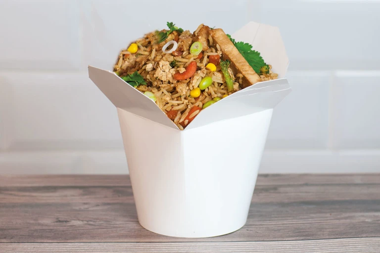 A white Chinese takeout container filled with air fryer fried rice made with Quorn Vegan Fillets.