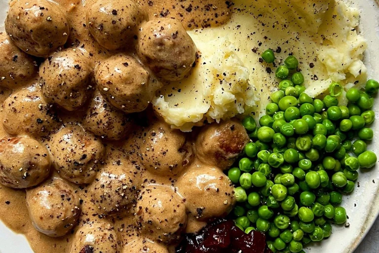 Quorn Meatballs and creamy gravy with mash, peas and jam, sprinkled with black pepper. 