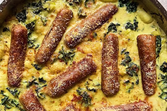 A portion of creamy leeks and greens gnocchi with the Quorn vegetarian sausages visibly on top.