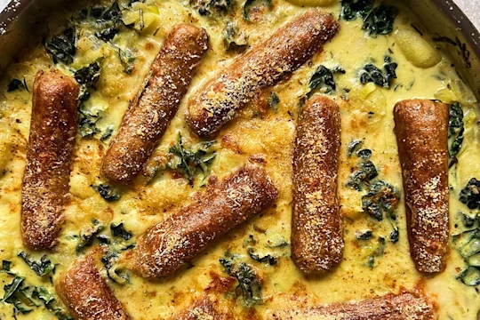 A portion of creamy leeks and greens gnocchi with the Quorn vegetarian sausages visibly on top.