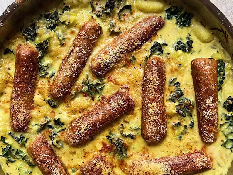 A portion of creamy leeks and greens gnocchi with the Quorn vegetarian sausages visibly on top.