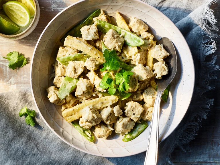 Easy Vegetarian Thai green curry served in a bowl, topped with mint with lime on the side.