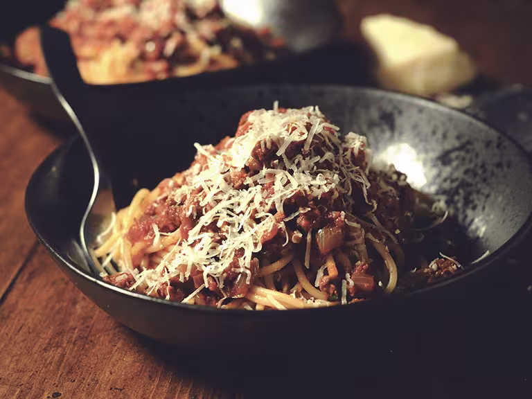 A bowl of spaghetti topped with Quorn Ground meat sauce and shredded parmesan cheese.