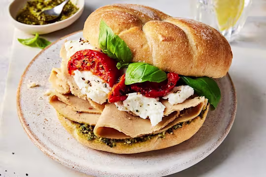 Vegan Roast Chicken Pesto Sandwich slightly opened to show the filling with sundried tomatoes, mozzarella and Quorn Vegan Chicken Slices.