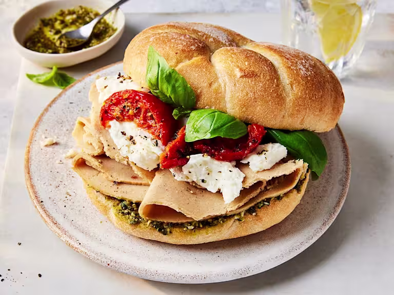 Vegan Roast Chicken Pesto Sandwich slightly opened to show the filling with sundried tomatoes, mozzarella and Quorn Vegan Chicken Slices.