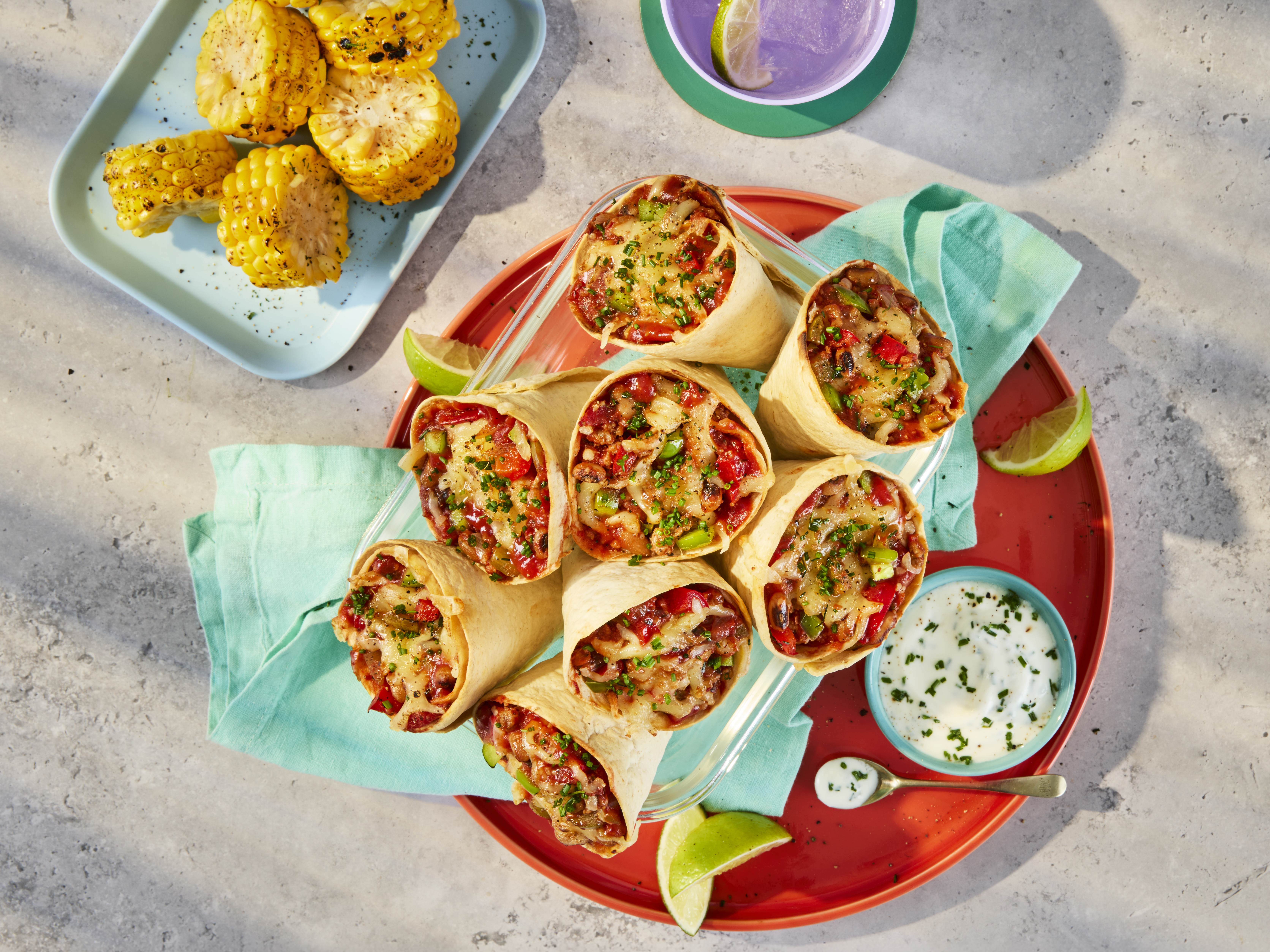 Tortilla cones filled with Quorn Mince, black-eyed beans and peppers in a tomato sauce, topped with mozzarella cheese. Served on a plate with a yoghurt and chive dip.