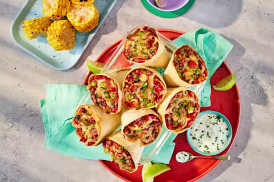 Tortilla cones filled with Quorn Mince, black-eyed beans and peppers in a tomato sauce, topped with mozzarella cheese. Served on a plate with a yoghurt and chive dip.